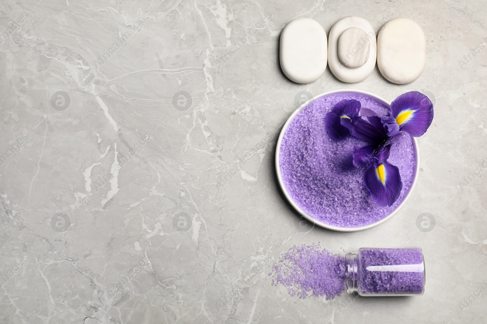 Photo of Plate and jar with purple sea salt, beautiful flower, spa stones on grey marble table, flat lay. Space for text