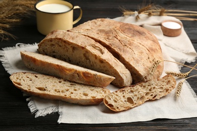 Photo of Tasty freshly baked bread on black wooden table