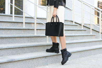 Photo of Young woman with stylish leather bag on stairs outdoors, closeup