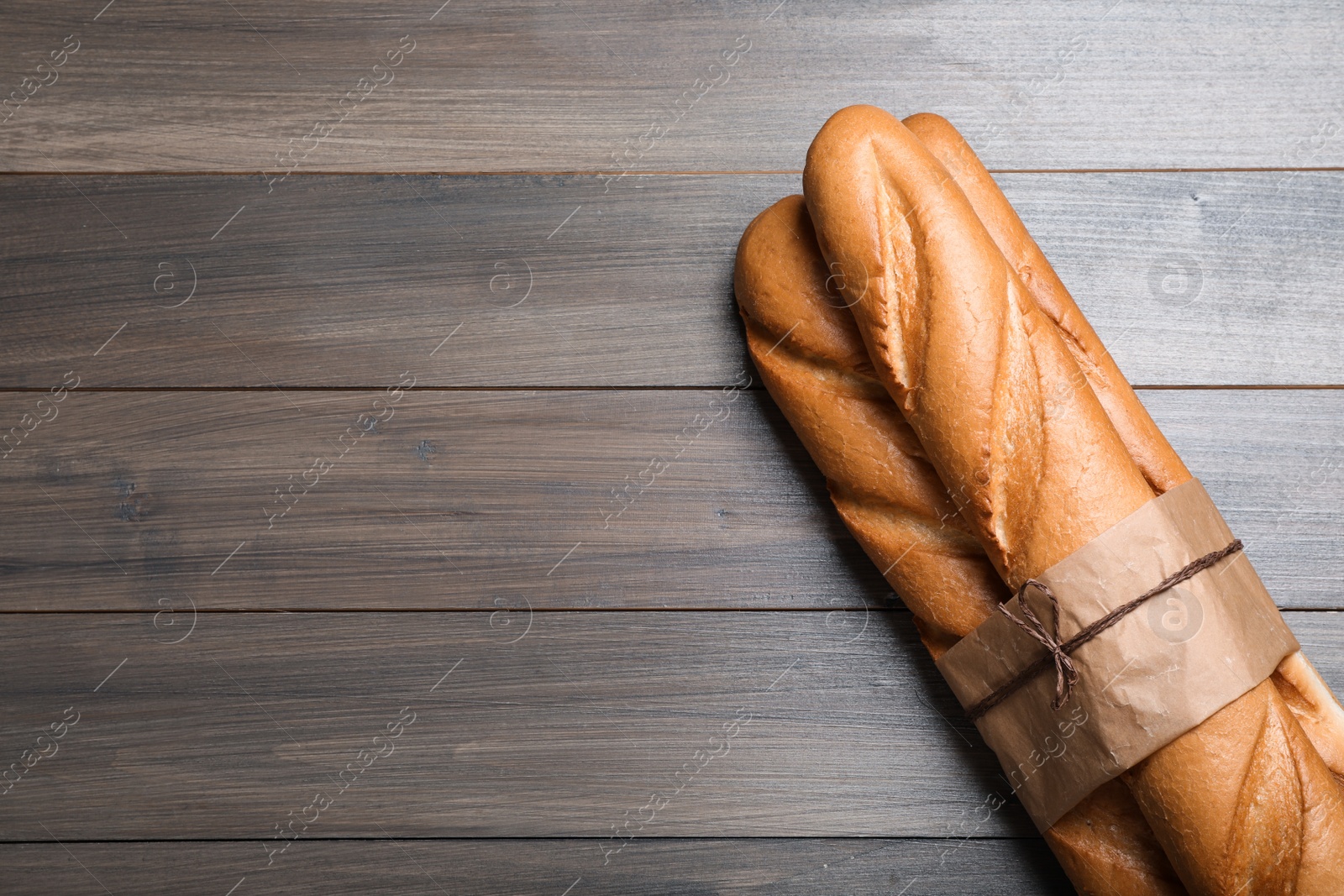 Photo of Bunch of tasty baguettes on wooden table, top view. Space for text