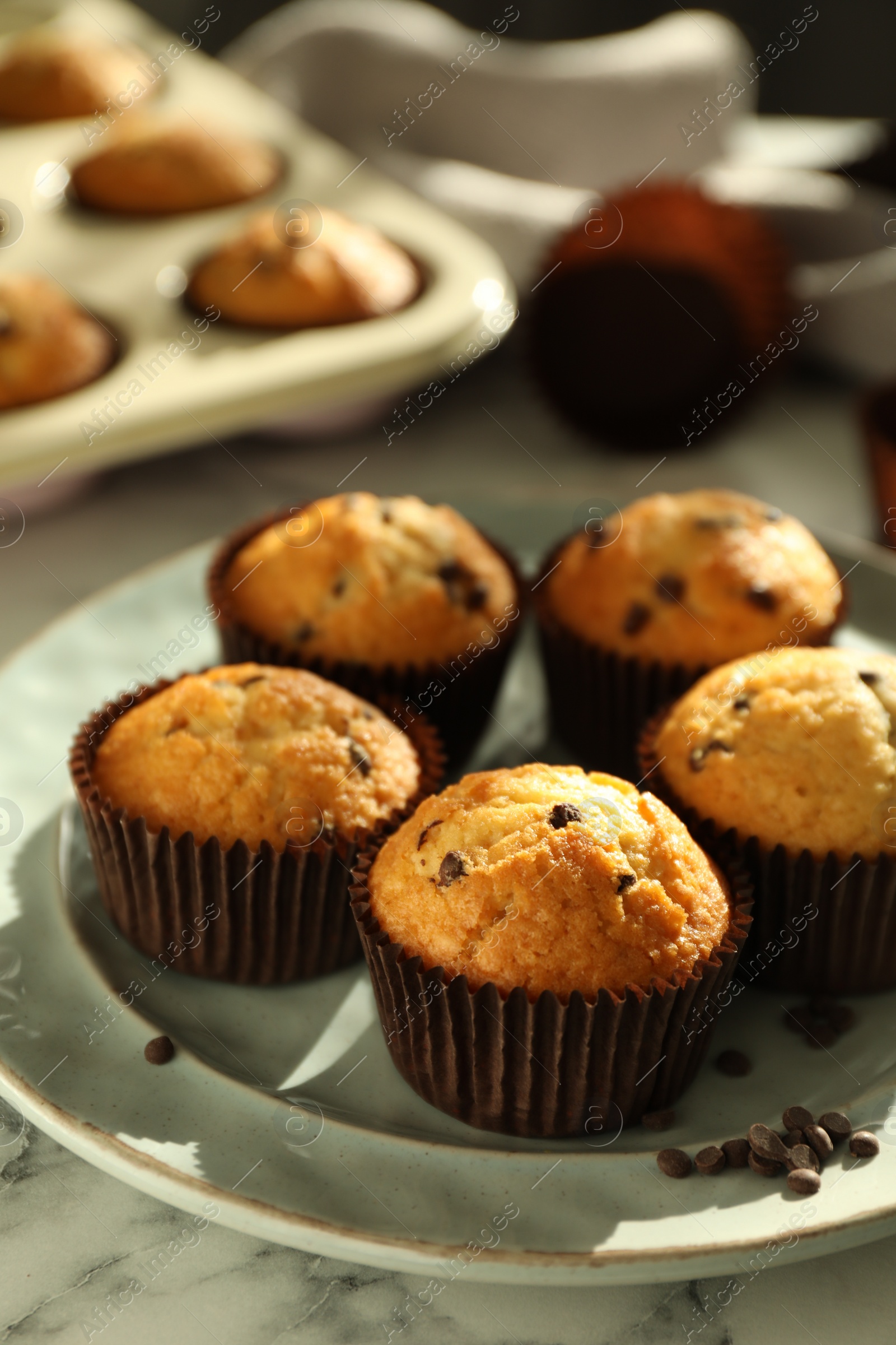 Photo of Delicious sweet muffins with chocolate chips on white marble table