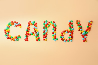 Photo of Word Candy made of tasty sweets on beige background, flat lay