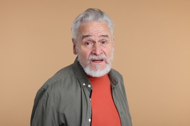 Photo of Portrait of surprised senior man on beige background