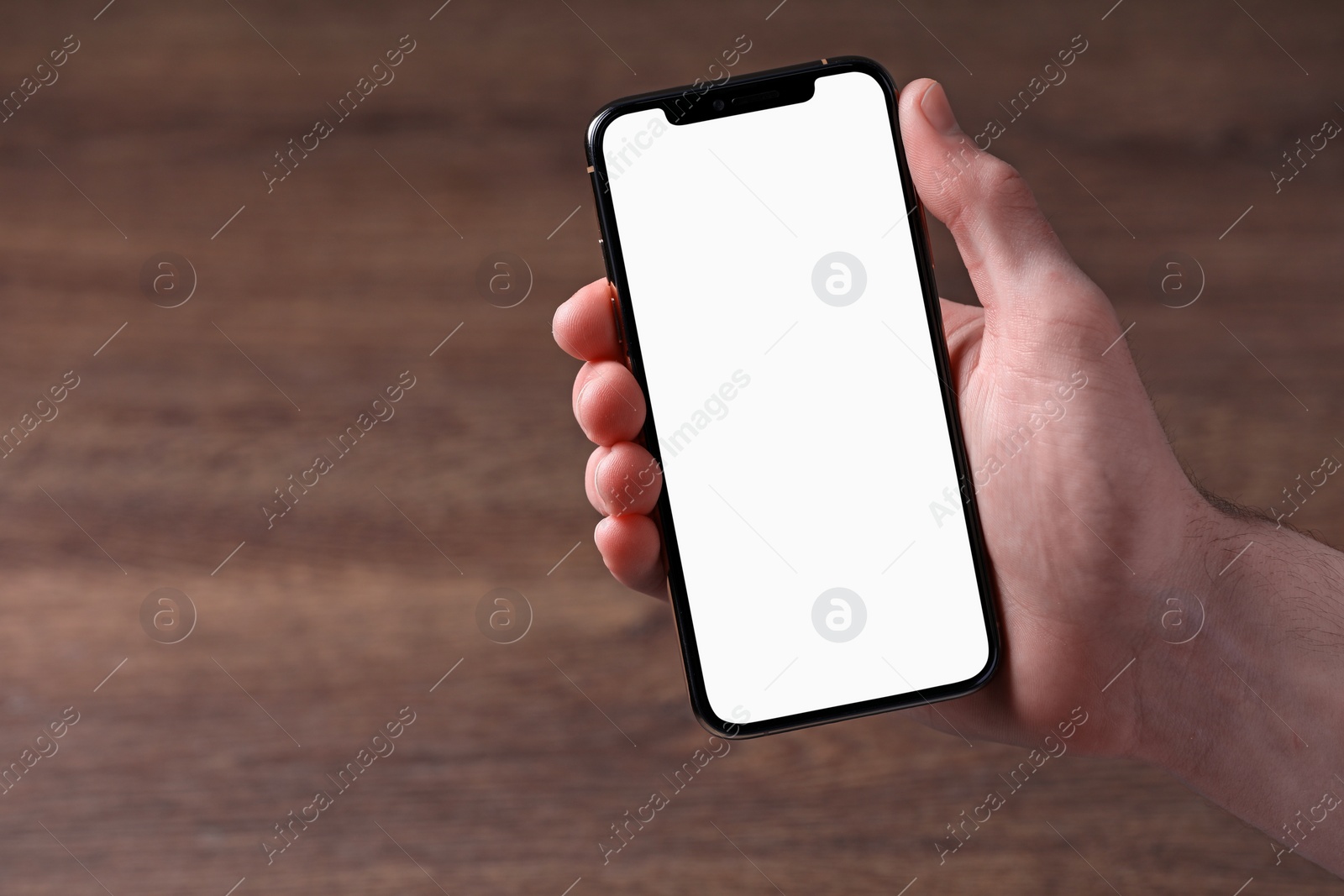 Photo of Man holding smartphone with blank screen at wooden table, top view. Mockup for design