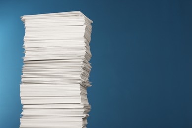 Photo of Stack of white paper sheets on blue background, space for text