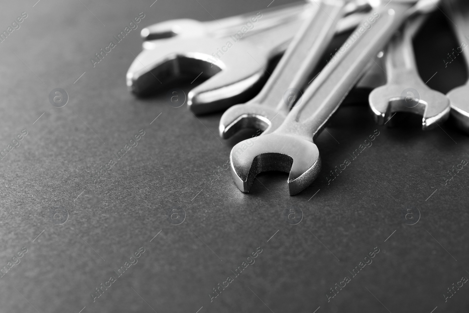 Photo of New wrenches on grey background, closeup with space for text. Plumber tools