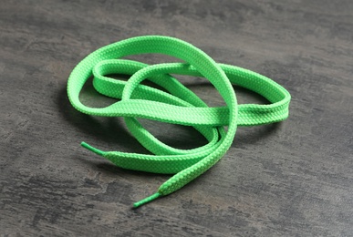 Photo of Green shoelace on grey stone background. Stylish accessory