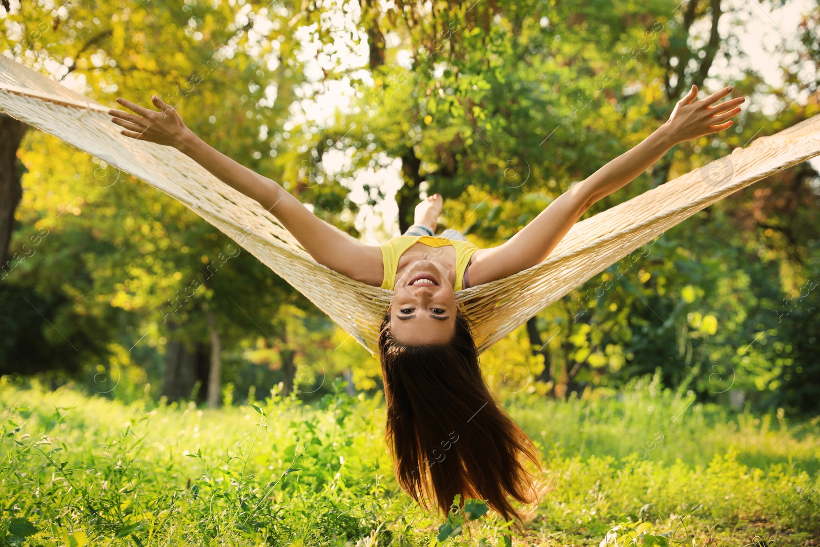 Photo of Young woman resting in comfortable hammock at green garden