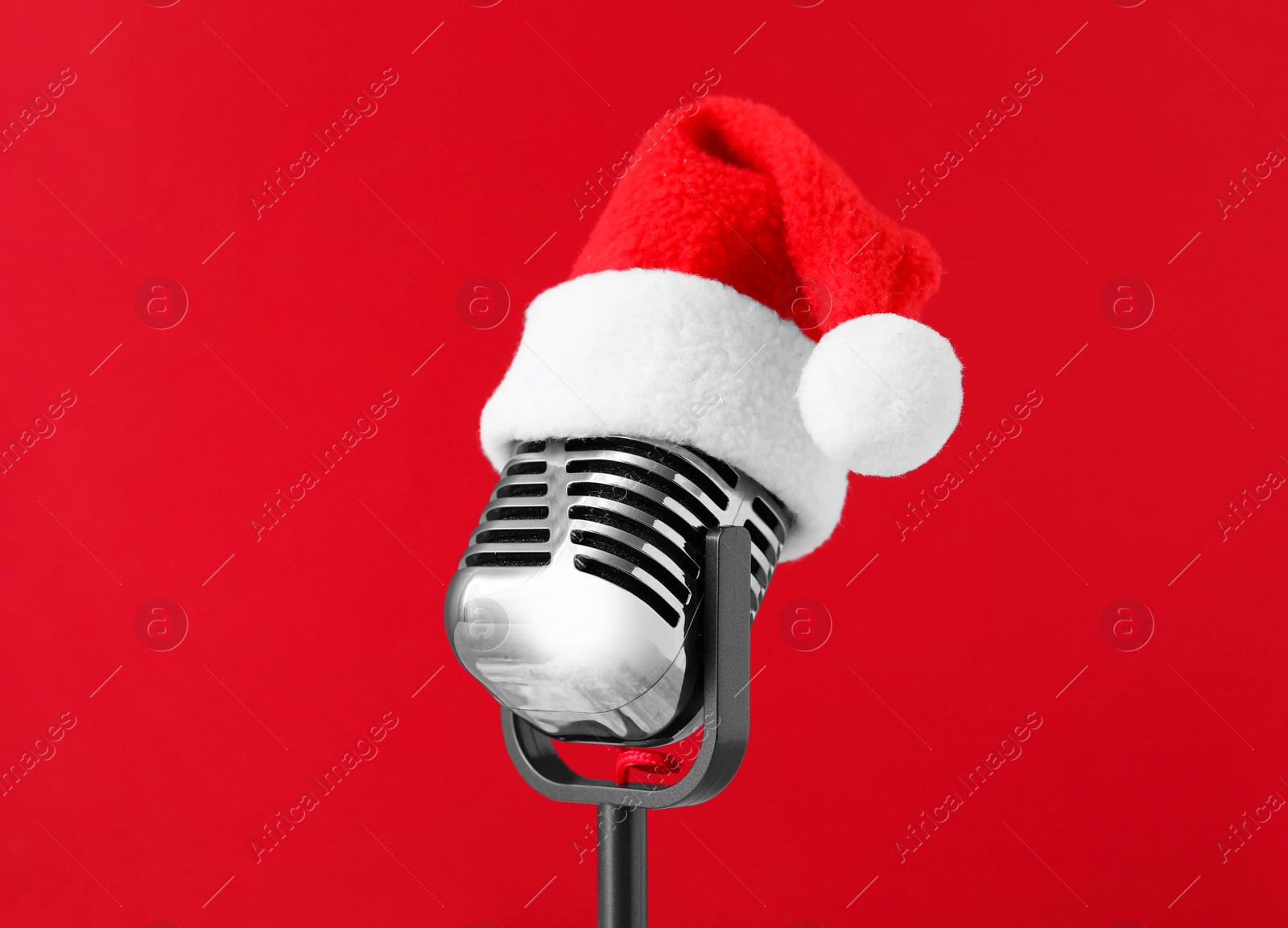 Photo of Retro microphone with Santa hat on red background. Christmas music