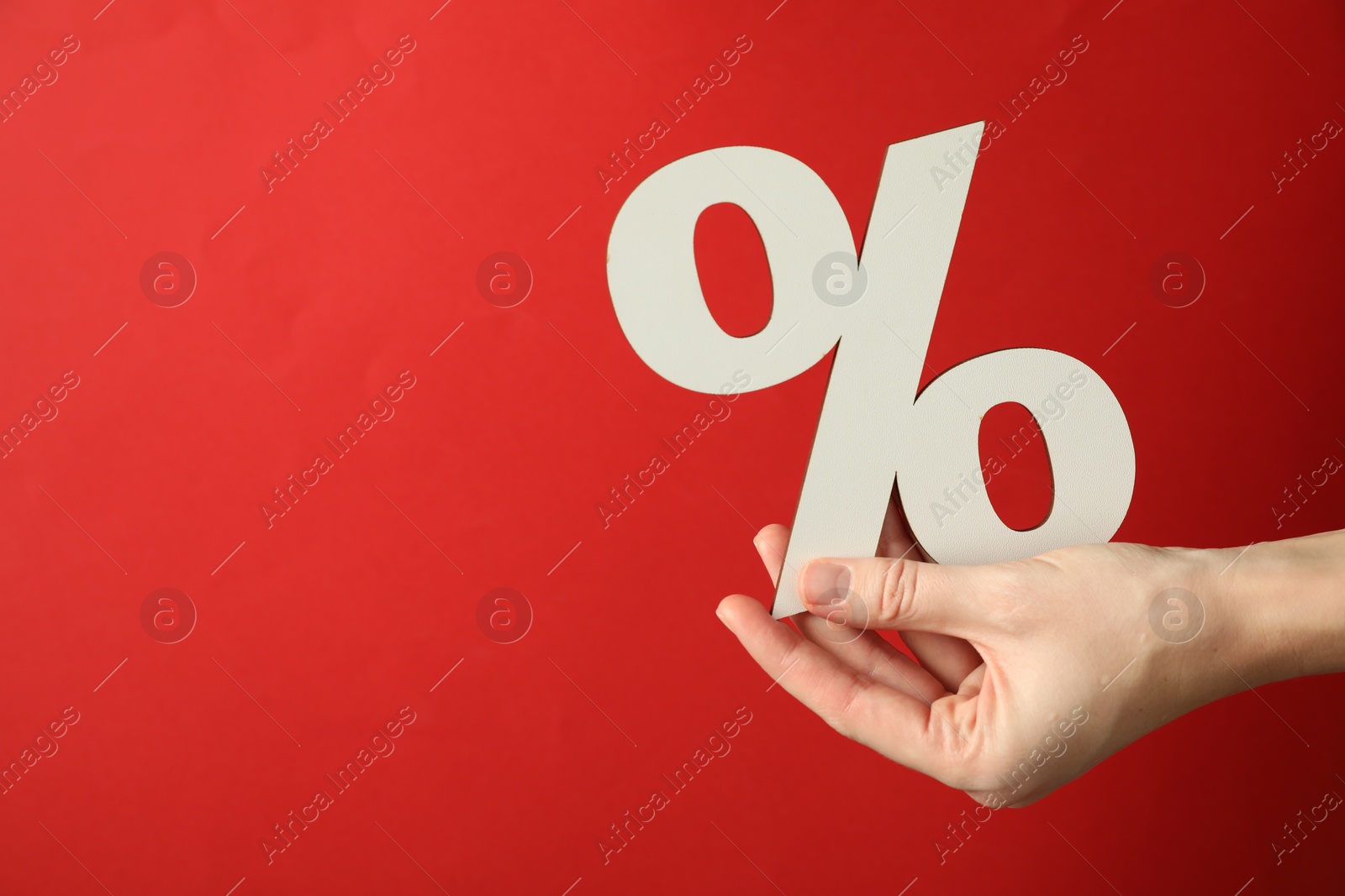 Photo of Woman holding percent sign on red background, closeup. Space for text