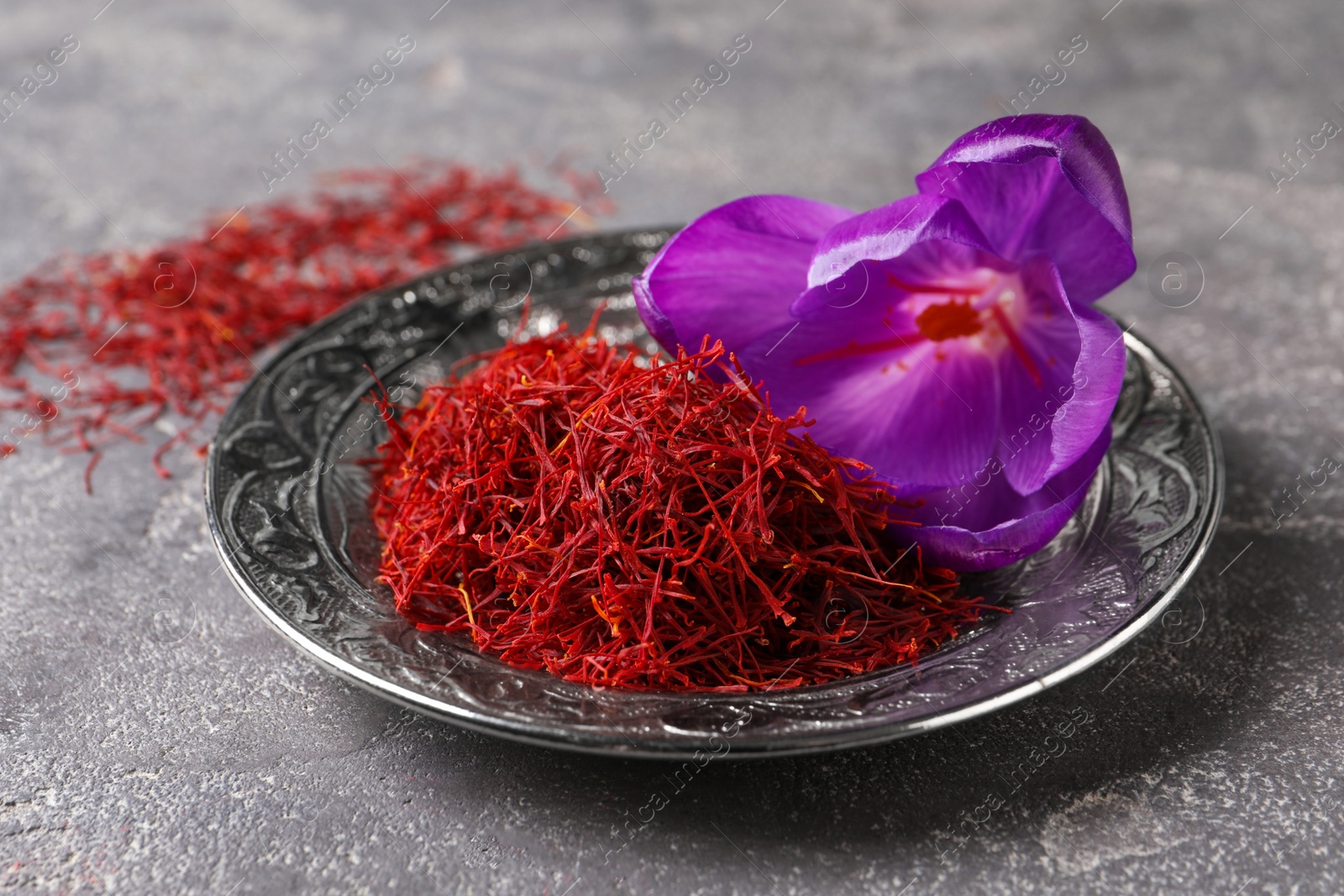 Photo of Dried saffron and crocus flower on grey table, closeup