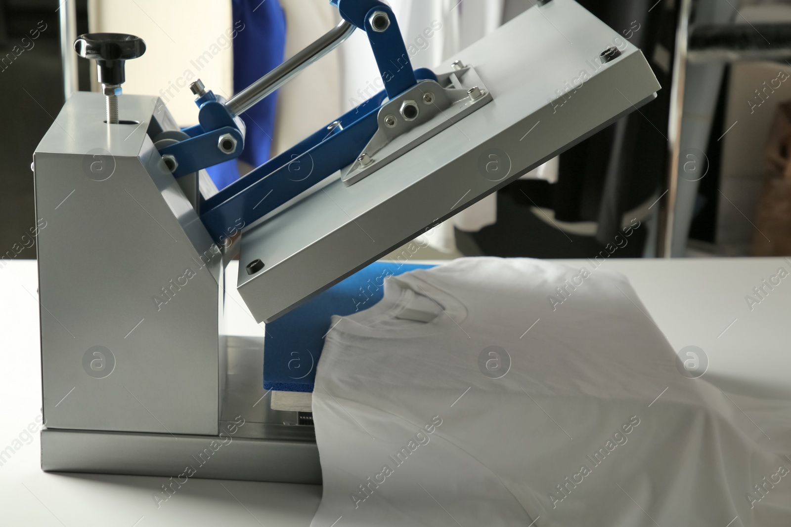 Photo of Printing logo. Heat press with t-shirt on white table