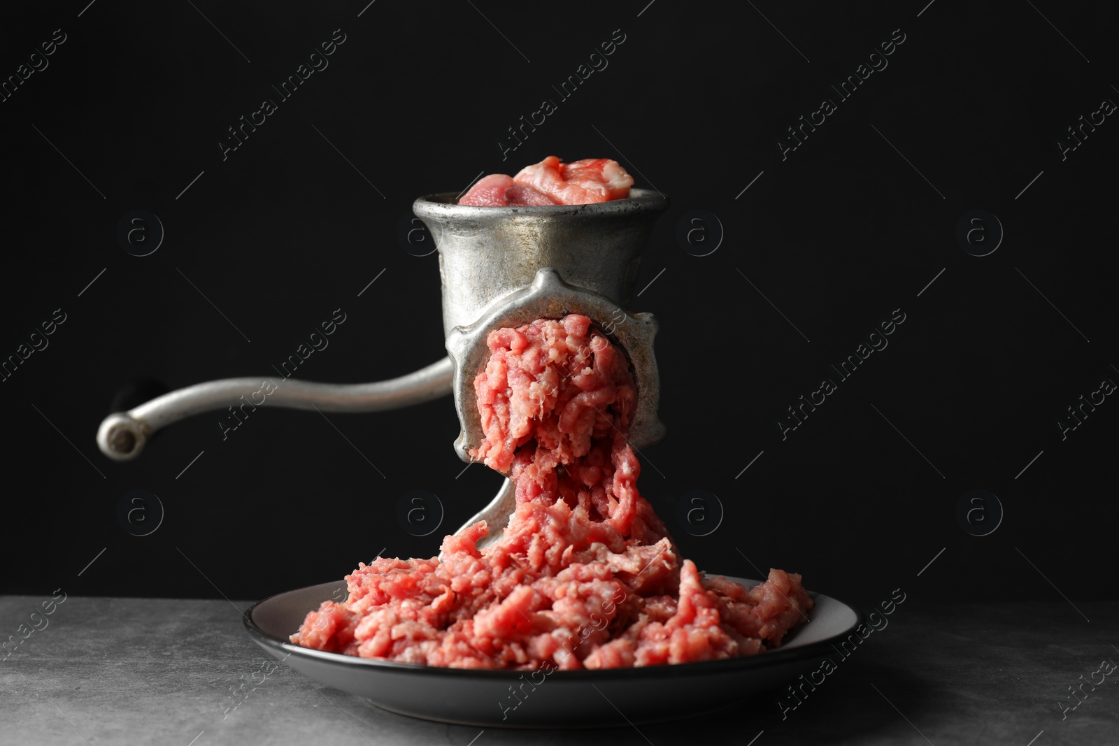 Photo of Manual meat grinder with beef mince on grey table