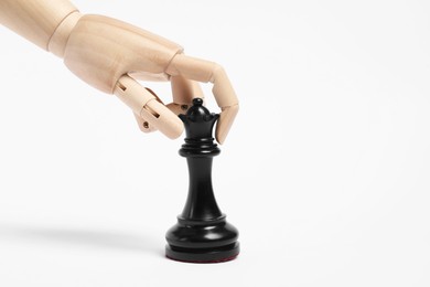 Photo of Robot with black chess piece on white background. Wooden hand representing artificial intelligence