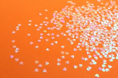 Photo of Shiny bright pink glitter on orange background