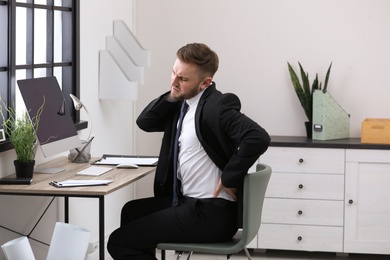 Photo of Businessman suffering from back pain at workplace