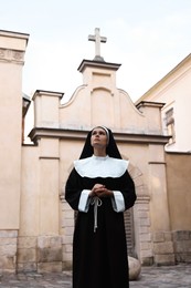 Beautiful young nun in cassock near cathedral outdoors