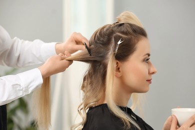 Photo of Hair styling. Professional hairdresser combing woman's hair indoors, closeup