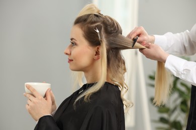 Photo of Hair styling. Professional hairdresser combing woman's hair indoors, closeup