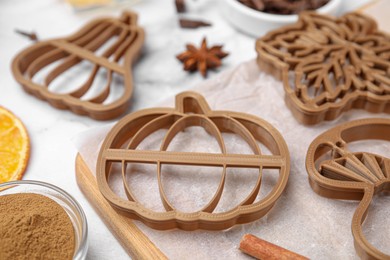 Cookie cutters of different shapes on white marble table, closeup