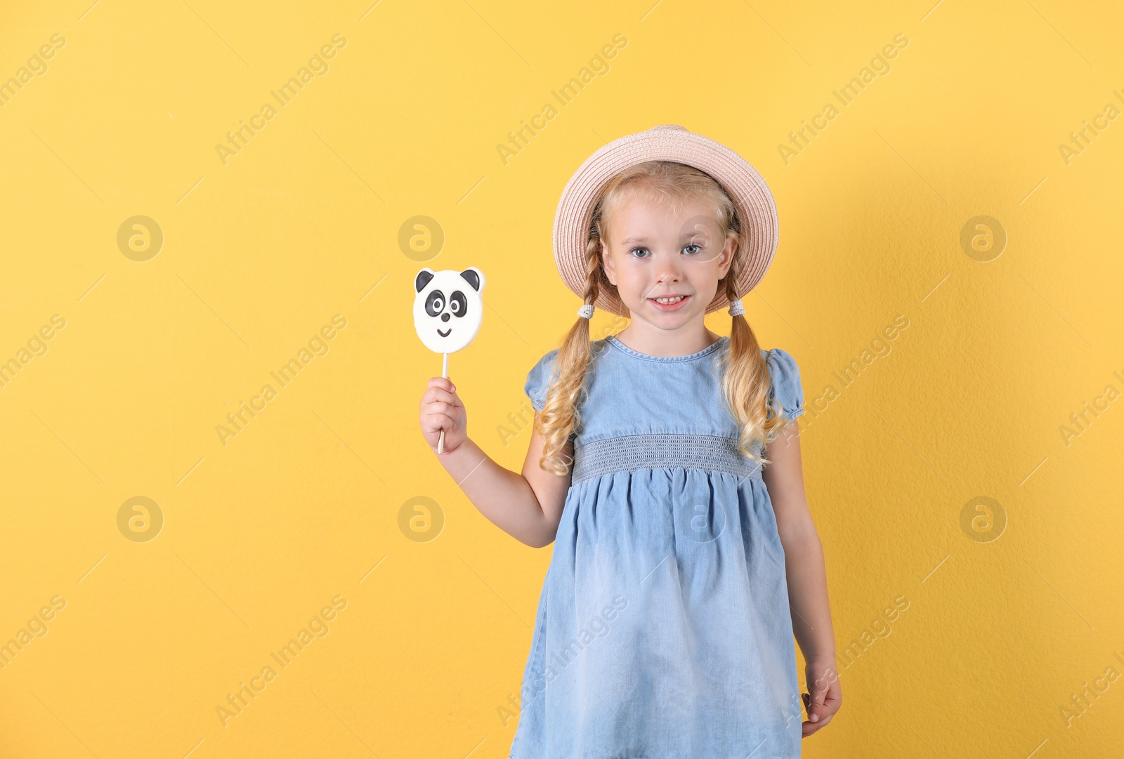 Photo of Cute little girl with candy on color background