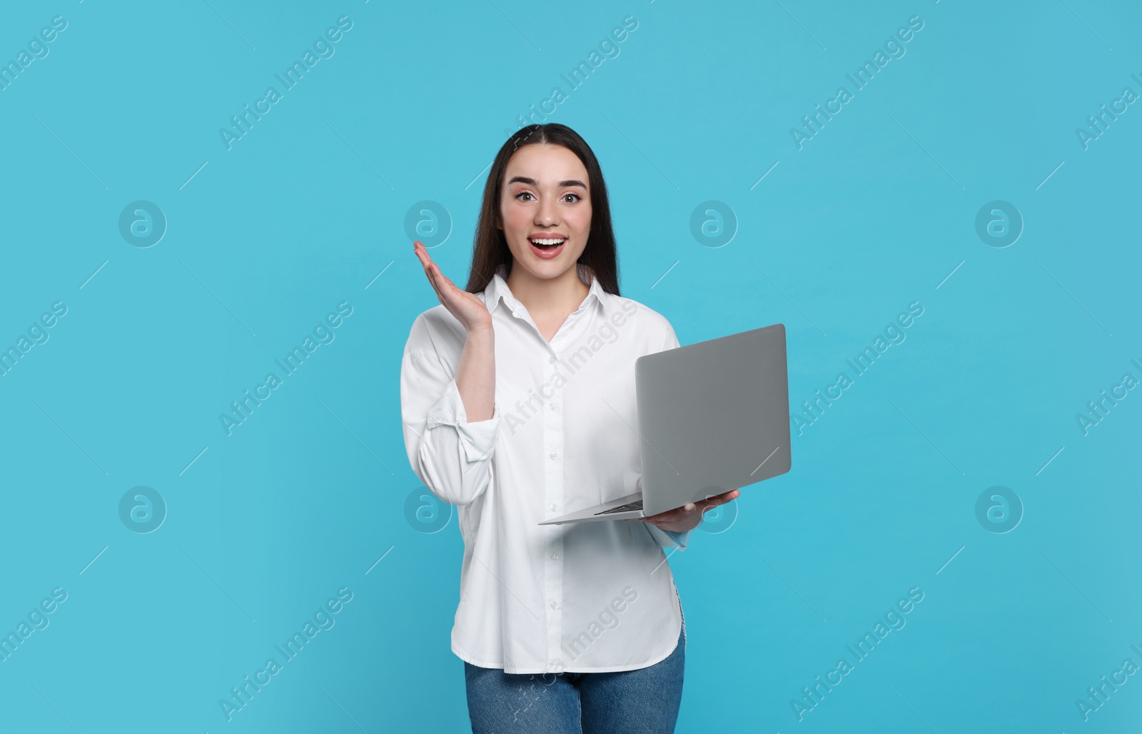 Photo of Surprised young woman with laptop on light blue background