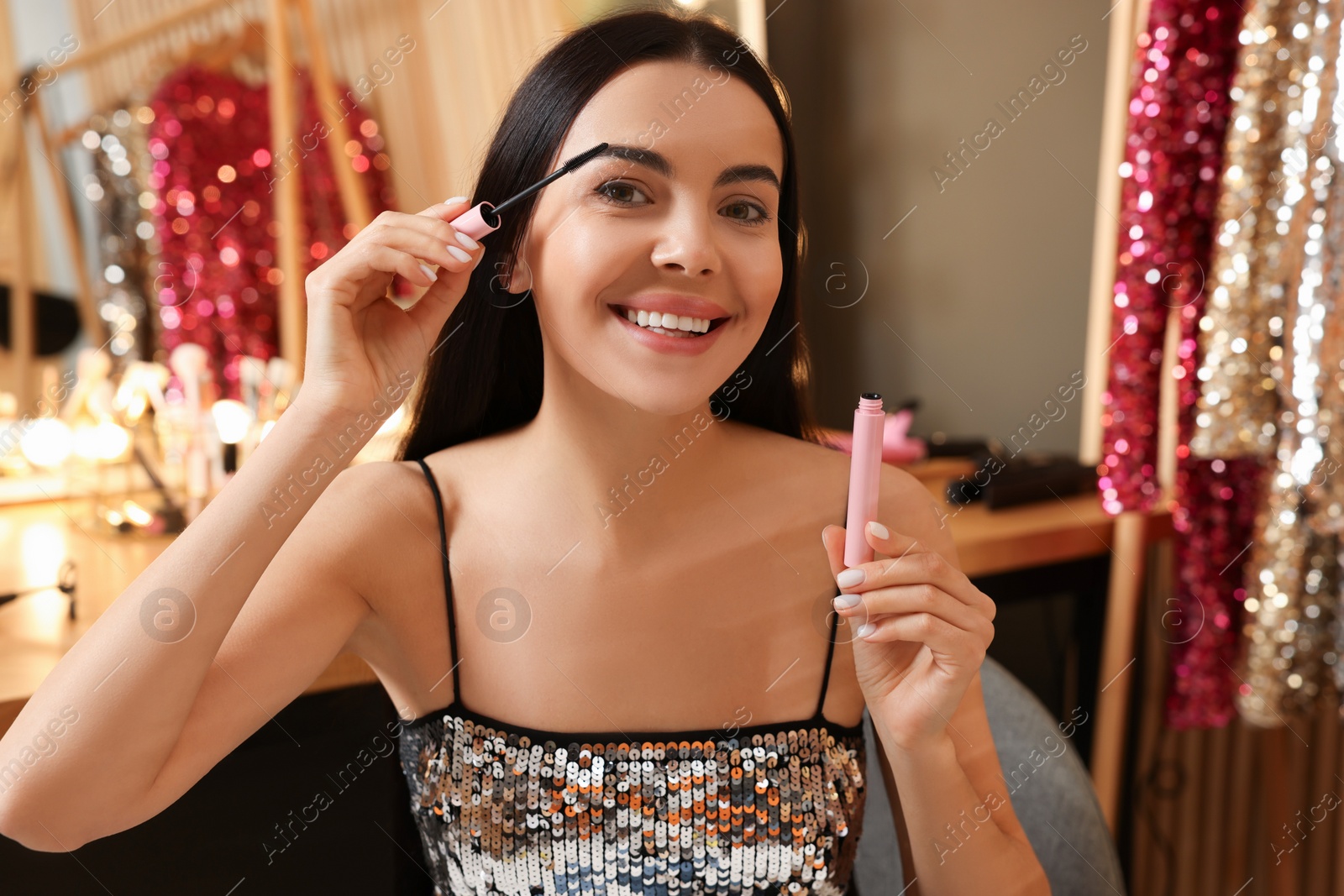 Photo of Beautiful young woman applying mascara in dressing room
