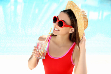 Photo of Woman with glass of refreshing drink near swimming pool