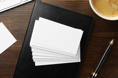 Photo of Blank business cards, notebook and pen on wooden table, flat lay. Mockup for design