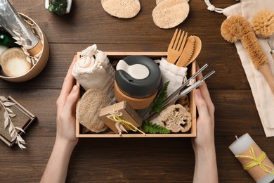 Woman with eco friendly products on wooden background, top view