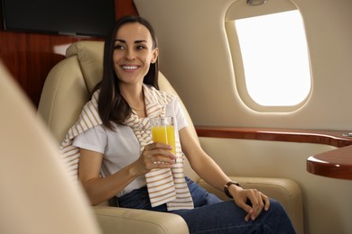 Photo of Young woman with glass of juice in airplane during flight