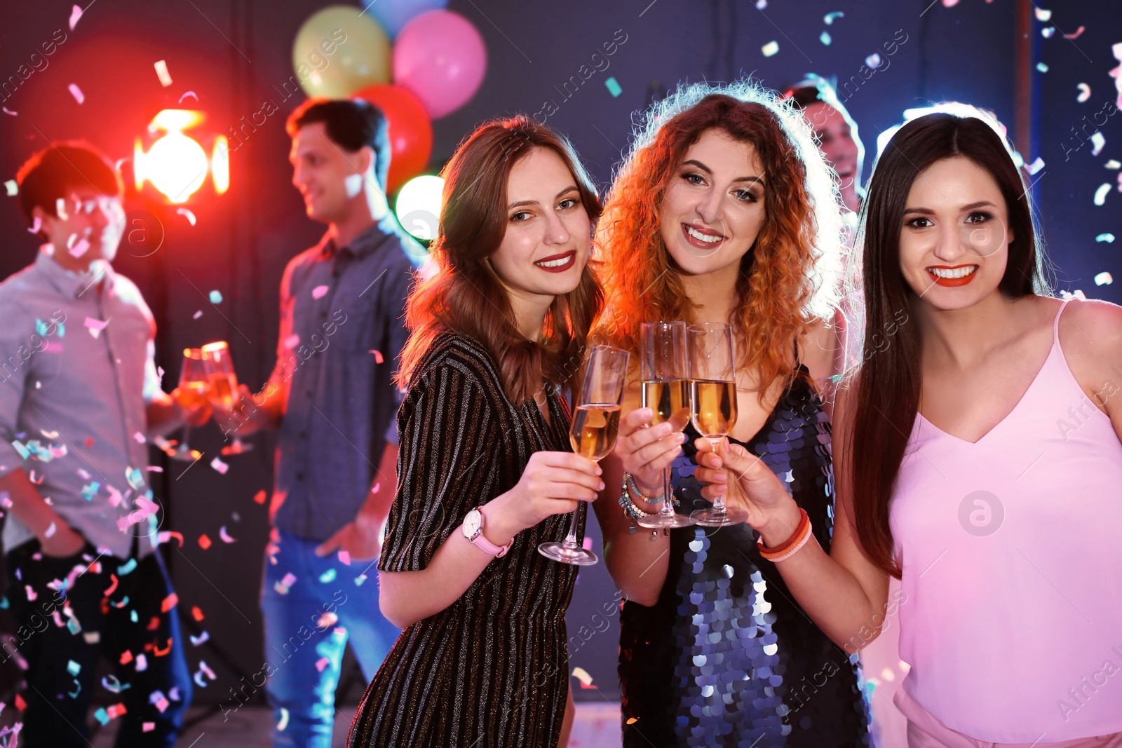 Photo of Young women chinking glasses in nightclub. Birthday party