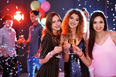 Photo of Young women chinking glasses in nightclub. Birthday party