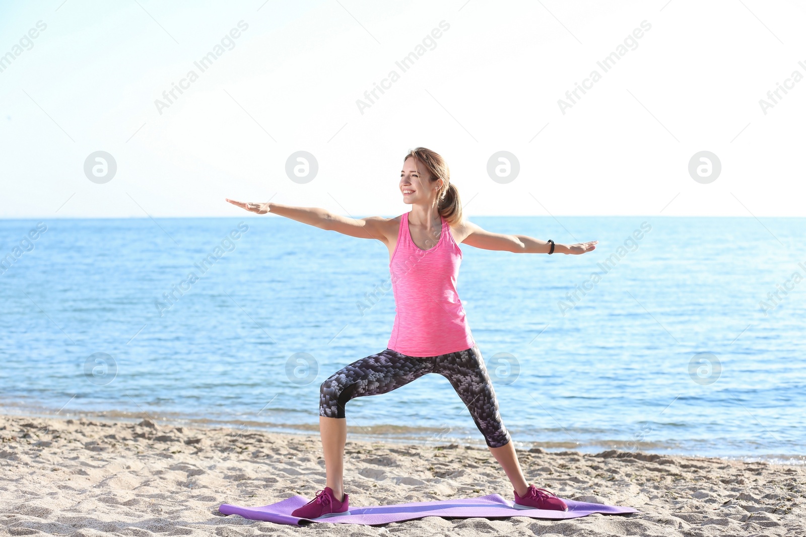 Photo of Young woman doing fitness exercises on beach in morning