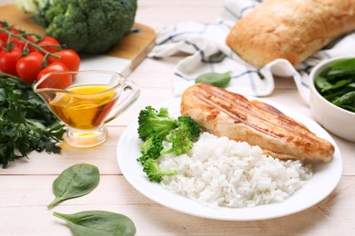 Grilled chicken breast and rice served with vegetables on wooden table