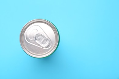 Photo of Energy drink in can on light blue background, top view. Space for text