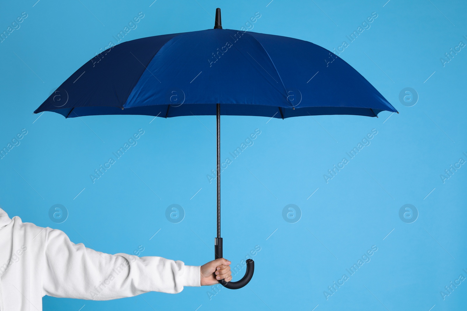 Photo of Woman with open bright umbrella on light blue background, closeup