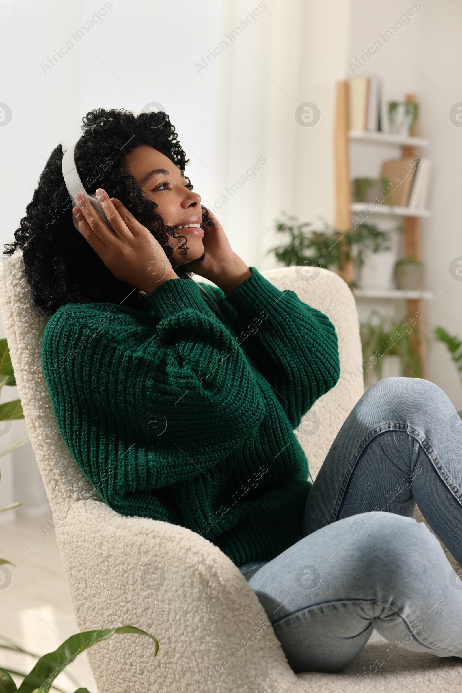 Photo of Relaxing atmosphere. Happy woman wearing headphones and listening music in room with beautiful houseplants