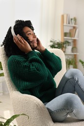 Relaxing atmosphere. Happy woman wearing headphones and listening music in room with beautiful houseplants