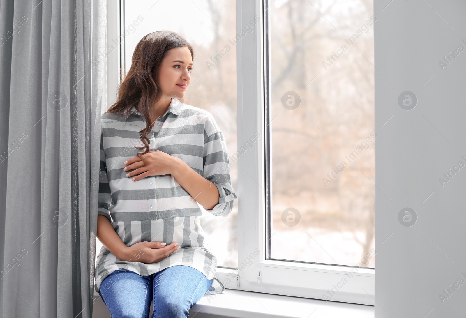 Photo of Beautiful pregnant woman near window at home