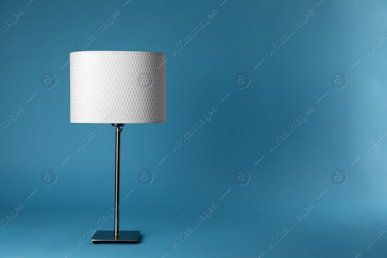 Photo of Stylish new night lamp on light blue background. Space for text