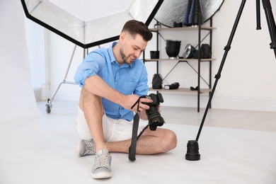 Photo of Professional photographer with camera and lighting equipment in studio