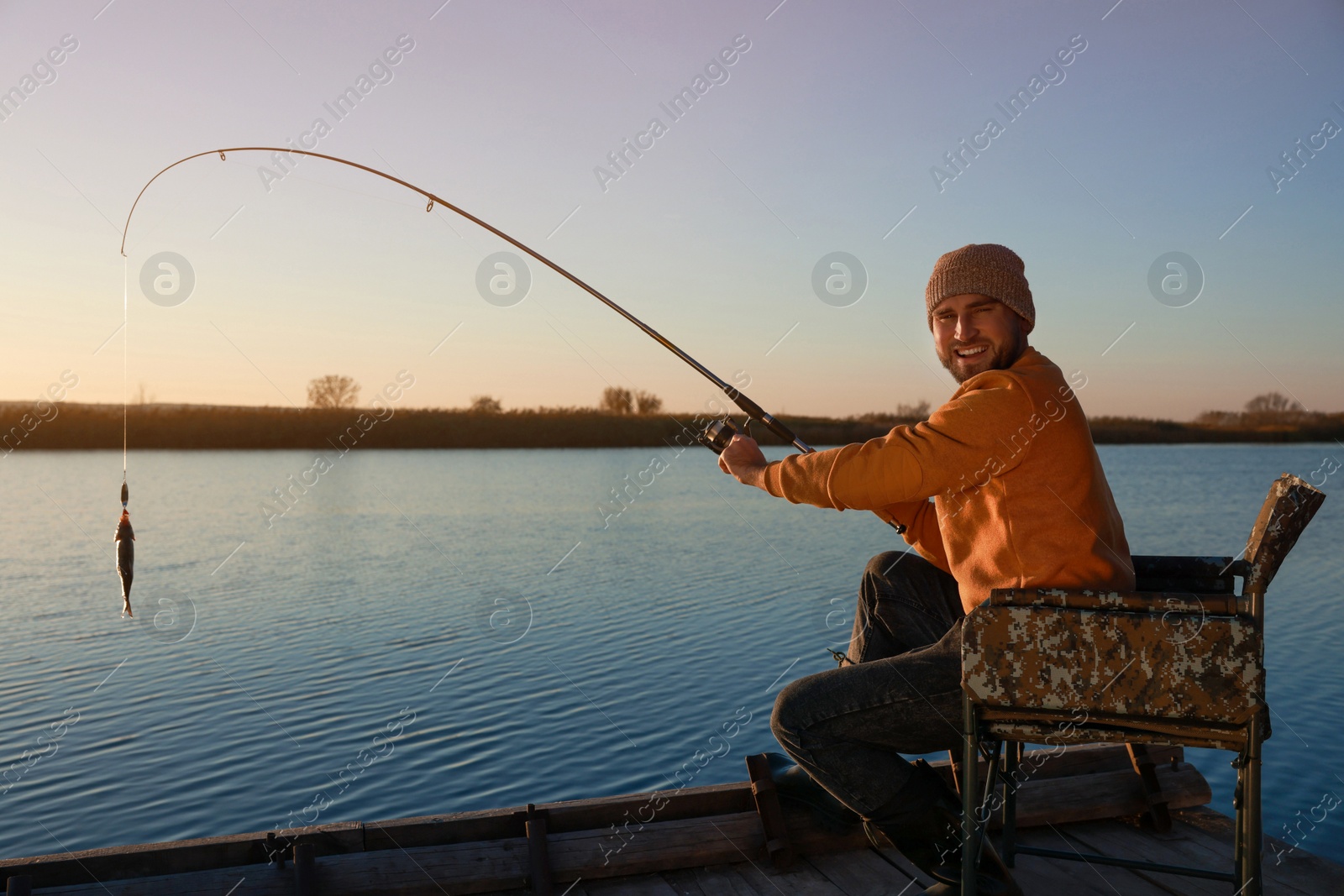 Photo of Fisherman catching fish with rod at riverside