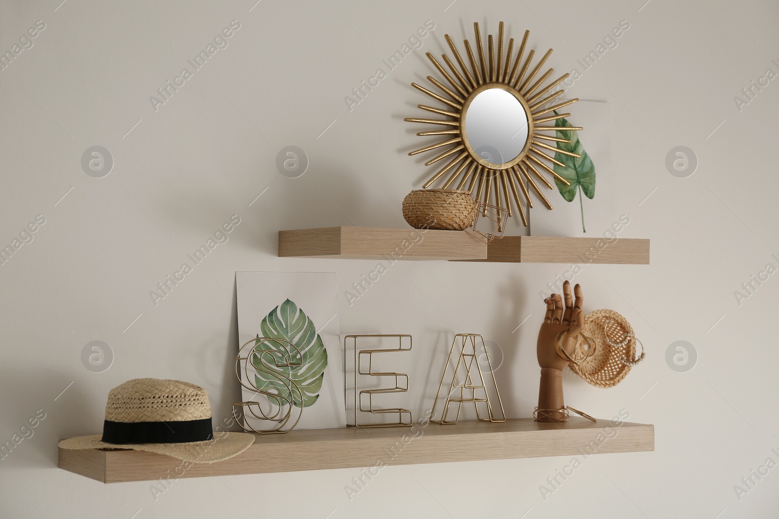 Photo of Wooden shelves with women's accessories and different decorative elements on light wall