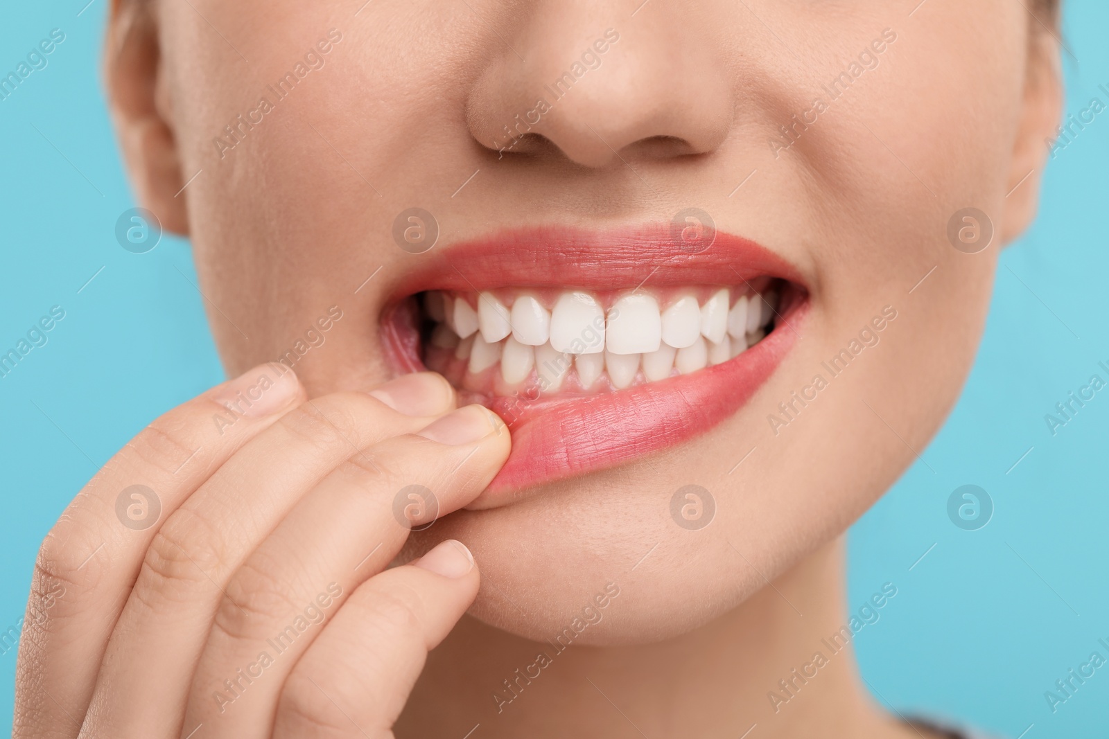 Photo of Woman showing her clean teeth on light blue background, closeup