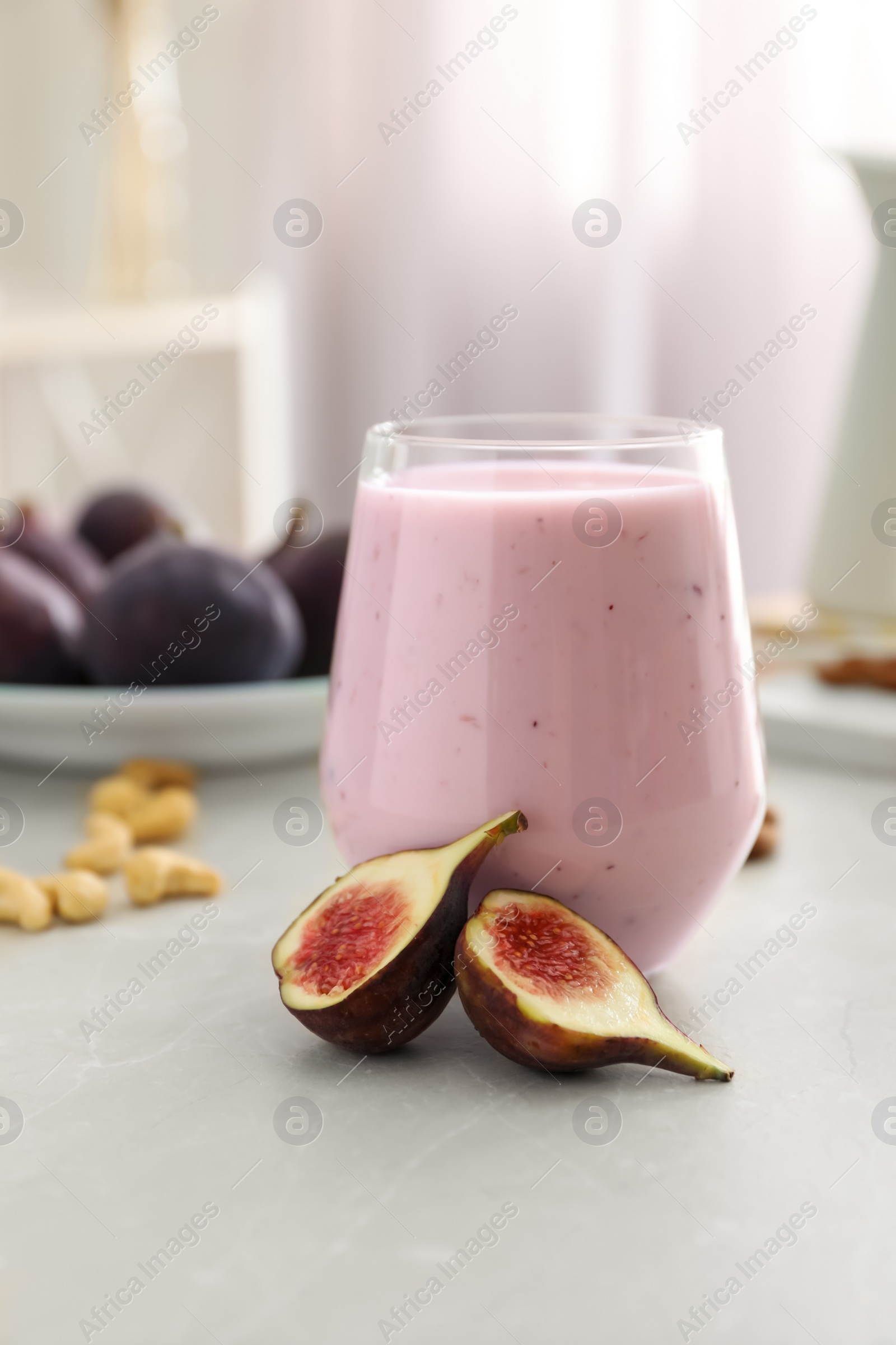 Photo of Delicious fig smoothie in glass on light table