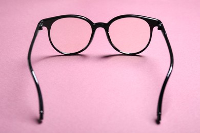 Stylish pair of glasses with black frame on pink background