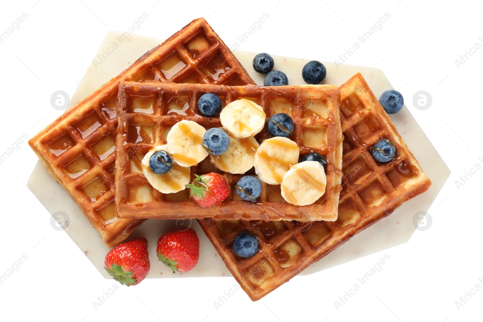 Photo of Board with delicious Belgian waffles, banana, berries and caramel sauce isolated on white, top view