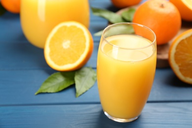 Delicious orange juice on blue wooden table, closeup. Space for text