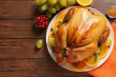 Photo of Platter of cooked turkey with garnish on wooden background, flat lay. Space for text